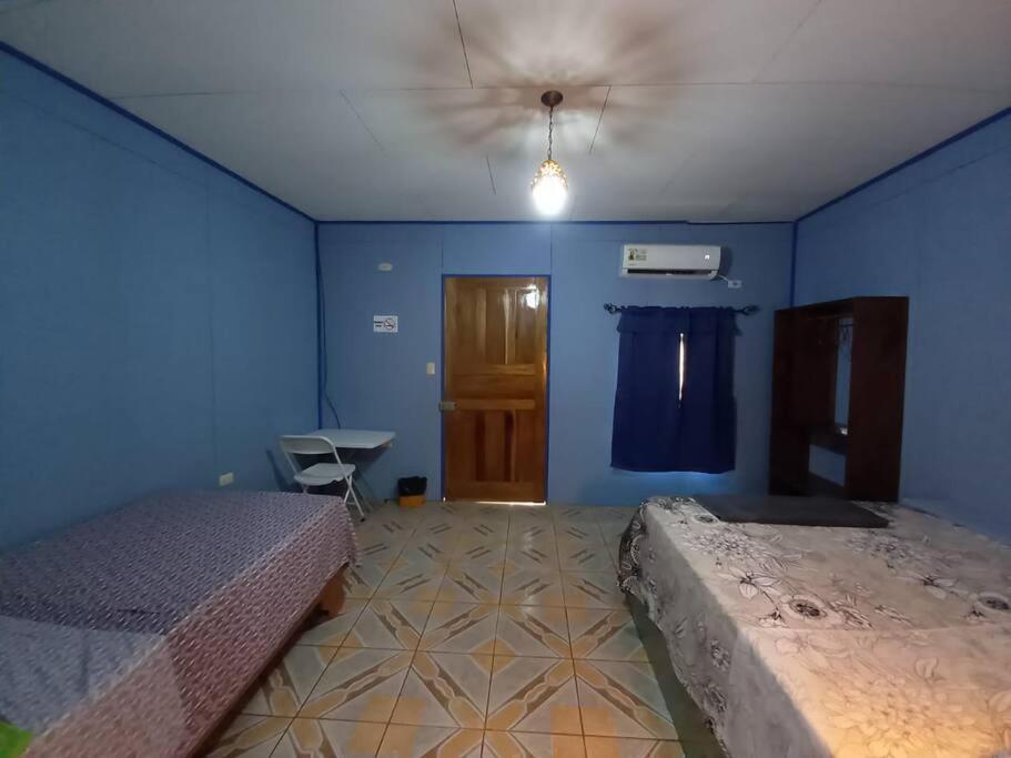 een slaapkamer met 2 bedden en een blauwe muur bij Cabinas Centro Social Volio #6 in Talamanca