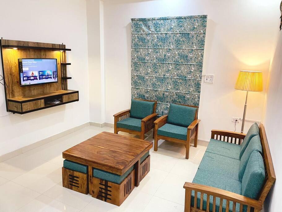 sala de estar con sofá, 2 sillas y TV en Utopiá 3BHK Entire Luxury Apartment In Noida 63, en Noida
