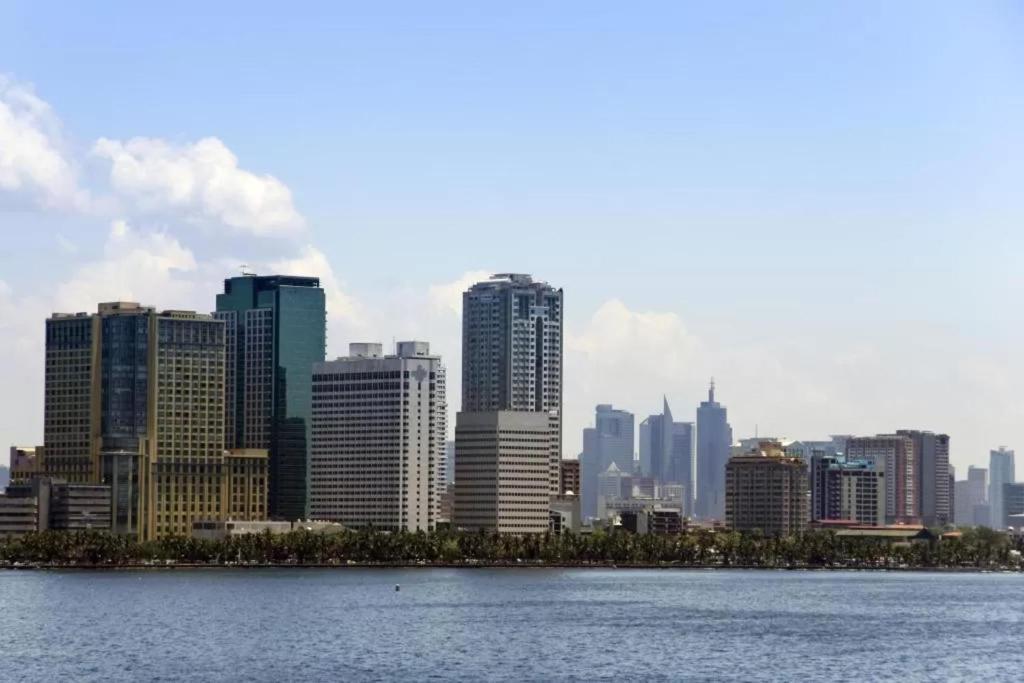 a city skyline with skyscrapers and a body of water at Experience OCEAN VIEW Rooms in The Heart Of Manila, Enjoy FREE ACCESS To The POOL, SAUNA, PLUS MASSAGE PROMO In Prime Location Near The US Embassy, NAIA, Makati, BGC, Mall of Asia, And Chinatown This Is A Limited-Time Offer, Book Now in Manila