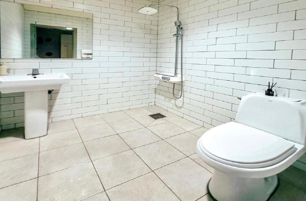 a white bathroom with a toilet and a sink at Halla guest house in Jeju