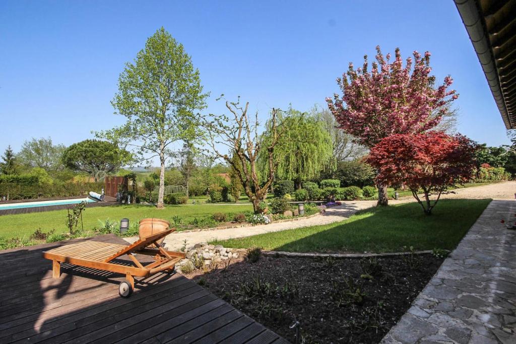 a wooden bench sitting on a deck in a garden at Gîte de France Bayat 4 épis - Gîte de France 5 personnes 354 in Varetz