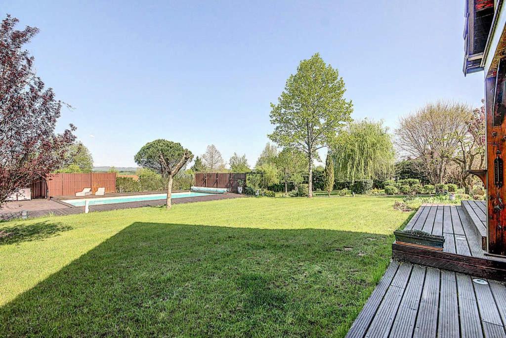 a yard with a wooden deck and a field of grass at Gîte de France Bayat 4 épis - Gîte de France 5 personnes 354 in Varetz