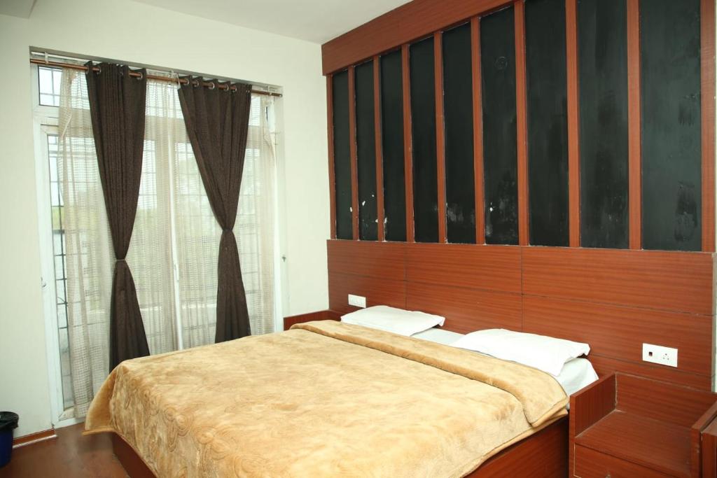 ウーティにあるTAT HOLIDAYS Armaan Groupsのベッドルーム1室(大型ベッド1台、木製ヘッドボード付)