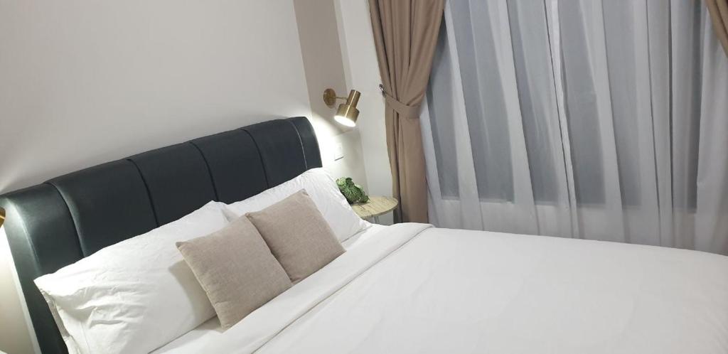 Schlafzimmer mit einem Bett mit weißer Bettwäsche und Kissen in der Unterkunft Homestay 2 Bedroom KLCC Wifi Netflix in Kuala Lumpur