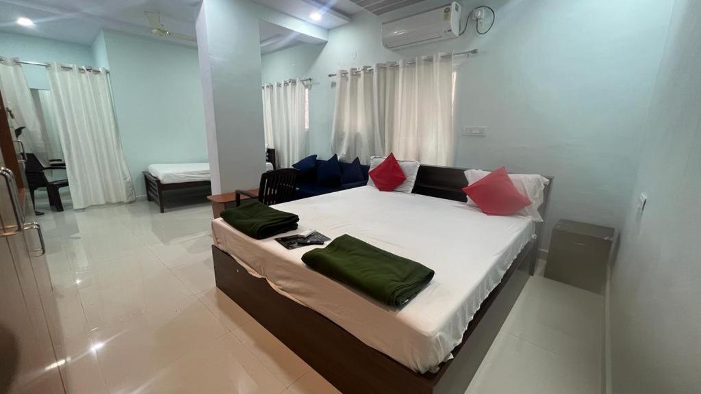 a bedroom with a large bed with red and green pillows at Brundavan in Hyderabad