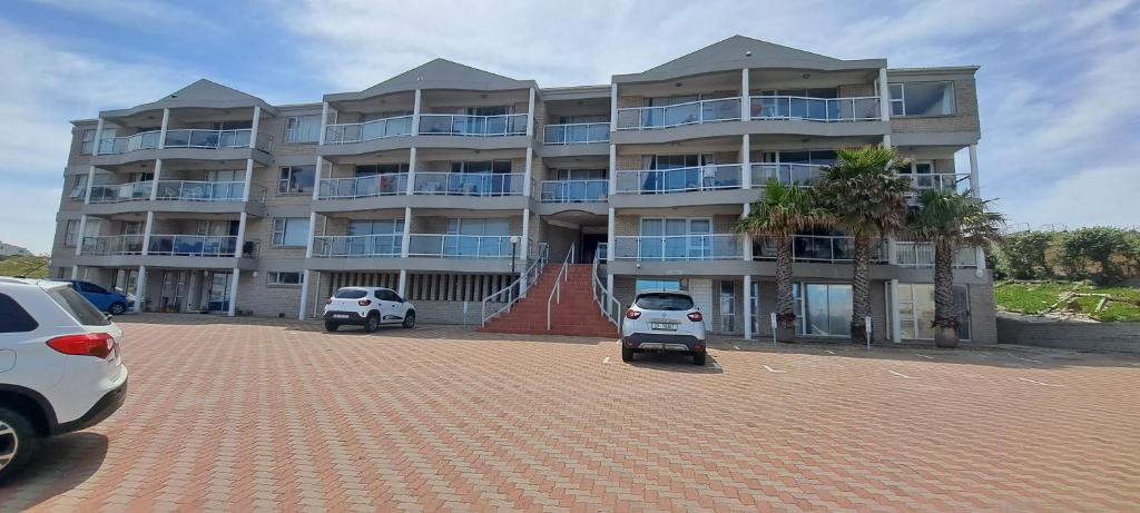 un gran edificio con coches estacionados frente a él en 201 Coral Island, 88 Coral Road, Bloubergstrand en Bloubergstrand