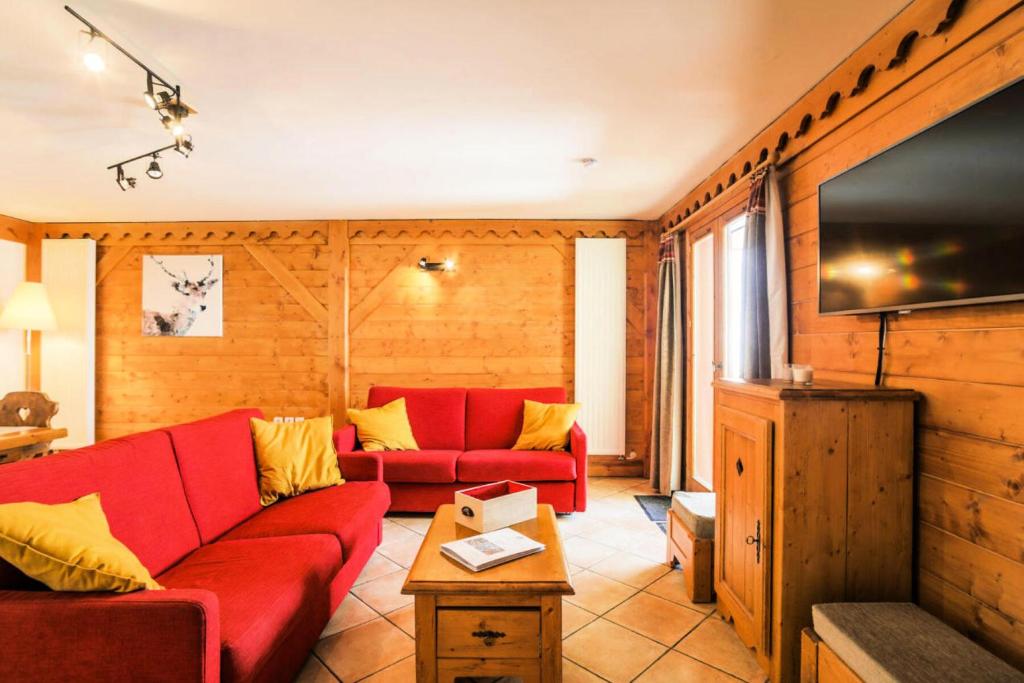 a living room with a red couch and a flat screen tv at Résidence Les Alpages de Reberty - maeva Home - Appartement 3 pièces 6 pers 26 in Les Menuires