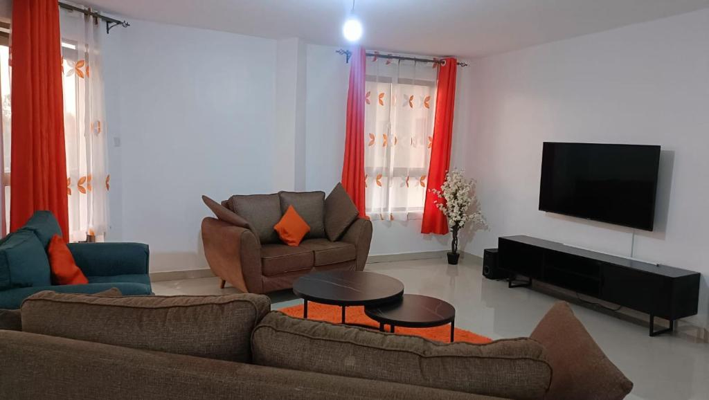 a living room with two couches and a flat screen tv at Runda Royale 3 bedroom apartment, Kiambu Road in Kiambu