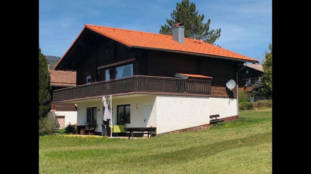 ein Haus mit einem orangenen Dach und einem Balkon in der Unterkunft Feriendorf am Hohen Bogen - Haus 66 in Arrach