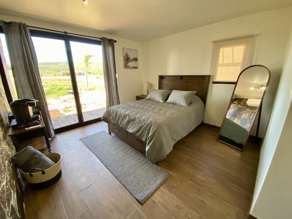 um quarto com uma cama e uma grande janela em Estancia Cataviña Valle de Guadalupe em Valle de Guadalupe