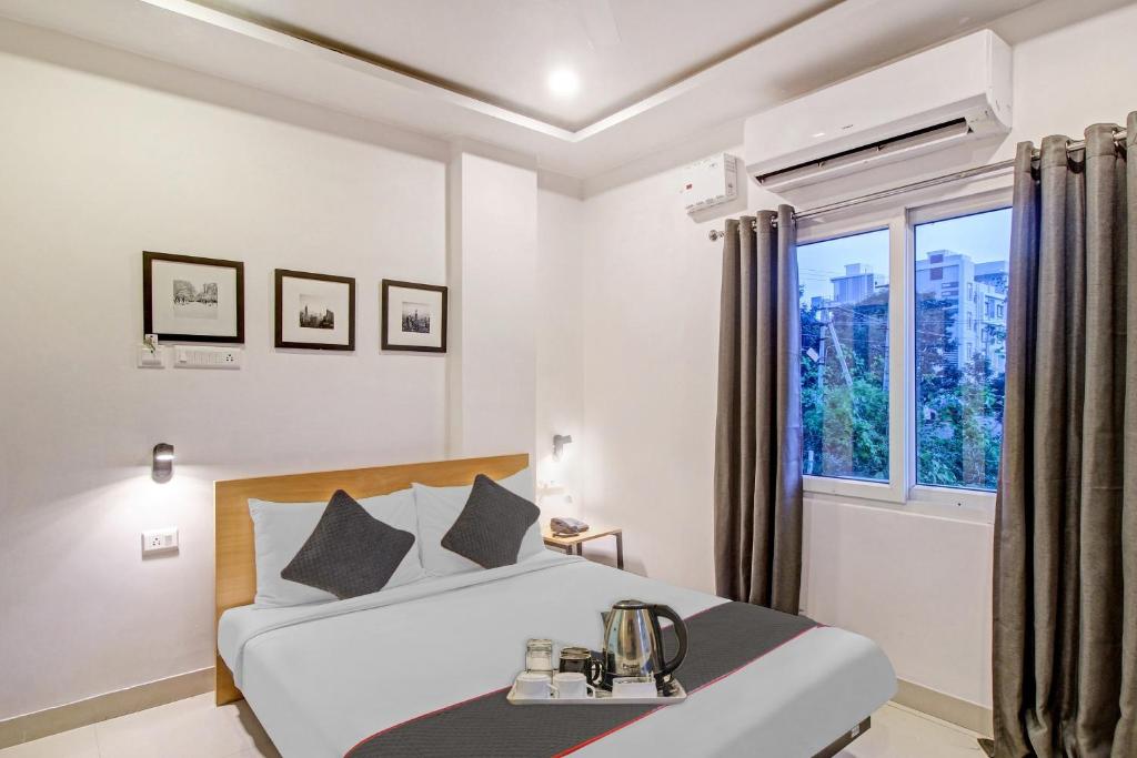 a white bedroom with a bed and a window at OYO Townhouse 572 SS SKYLINE in Shamshabad