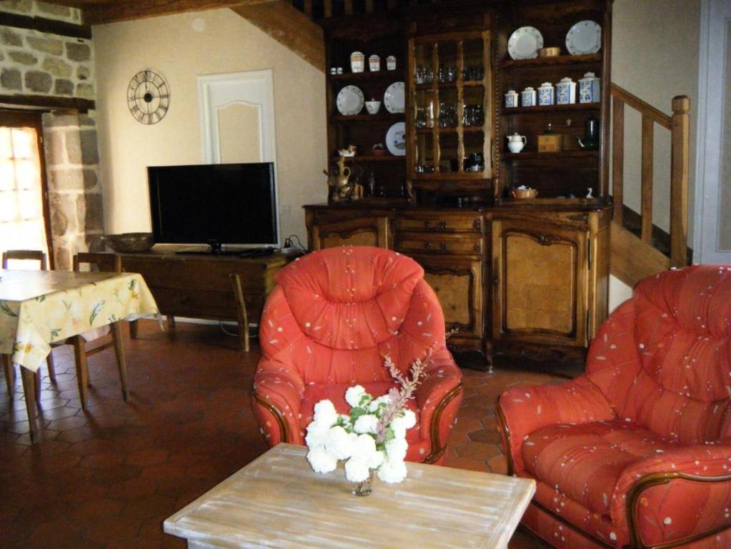ein Wohnzimmer mit 2 roten Stühlen und einem Tisch in der Unterkunft Gîte de France La bachellerie 2 épis - Gîte de France 5 personnes 264 
