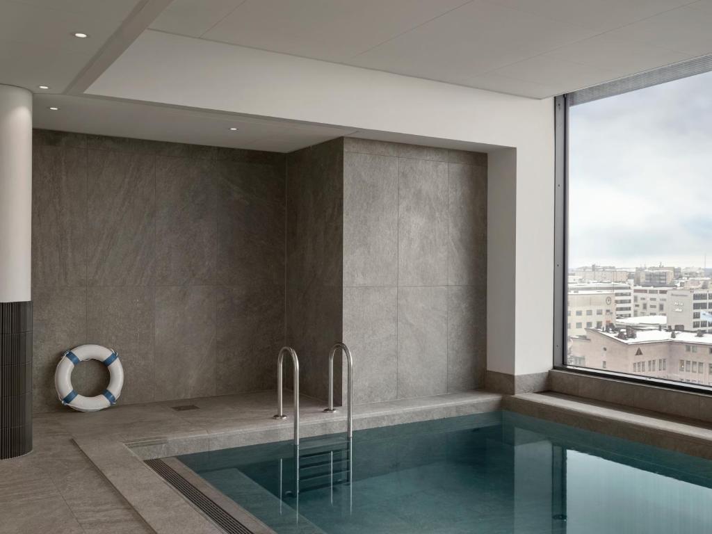 een badkamer met een zwembad en een groot raam bij Original Sokos Hotel Royal in Vaasa