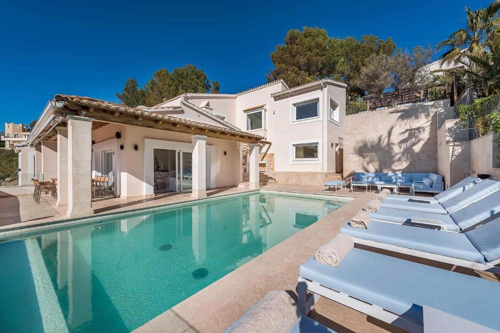 una piscina con 2 tumbonas y una casa en Villa Mar - Sol de Mallorca, en Sol de Mallorca
