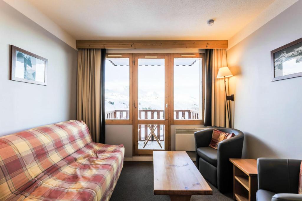 une chambre d'hôtel avec un canapé, une table et une fenêtre dans l'établissement Résidence Les Constellations - maeva Home - Appartement 2 Pièces 5 Personnes - Selection MAE-0341, à La Plagne Tarentaise