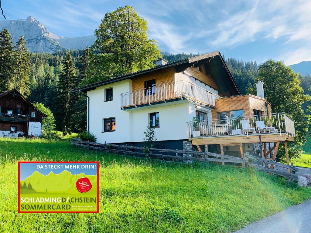 una casa en un campo con un cartel en el césped en Bergkristallhaus, en Ramsau am Dachstein