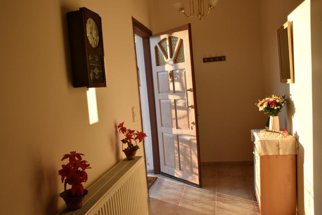 einen Flur mit einer Tür mit einer Uhr und Blumen in der Unterkunft Val's place in Mytilini