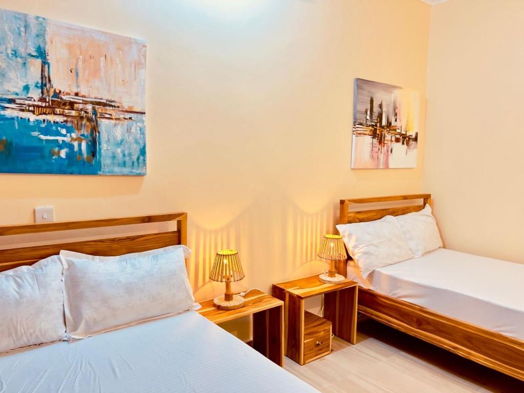 a bedroom with two beds and two lamps on tables at Pishon Home in Dar es Salaam
