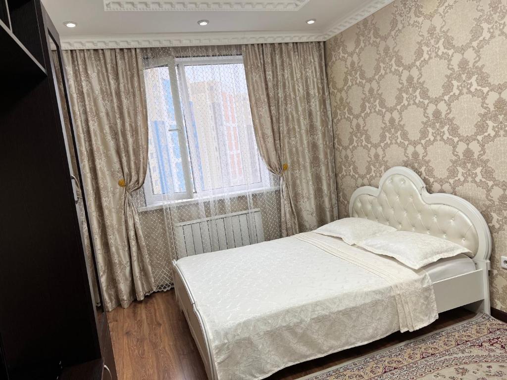 een slaapkamer met een wit bed en een raam bij Apartmens in Complex Almaly 83-51 in Alma-Ata