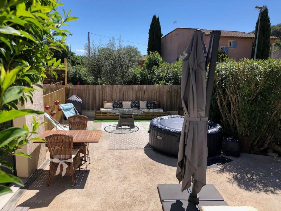 een patio met een tafel en een parasol bij Belle adresse pour un séjour détente et découverte in Trans-en-Provence