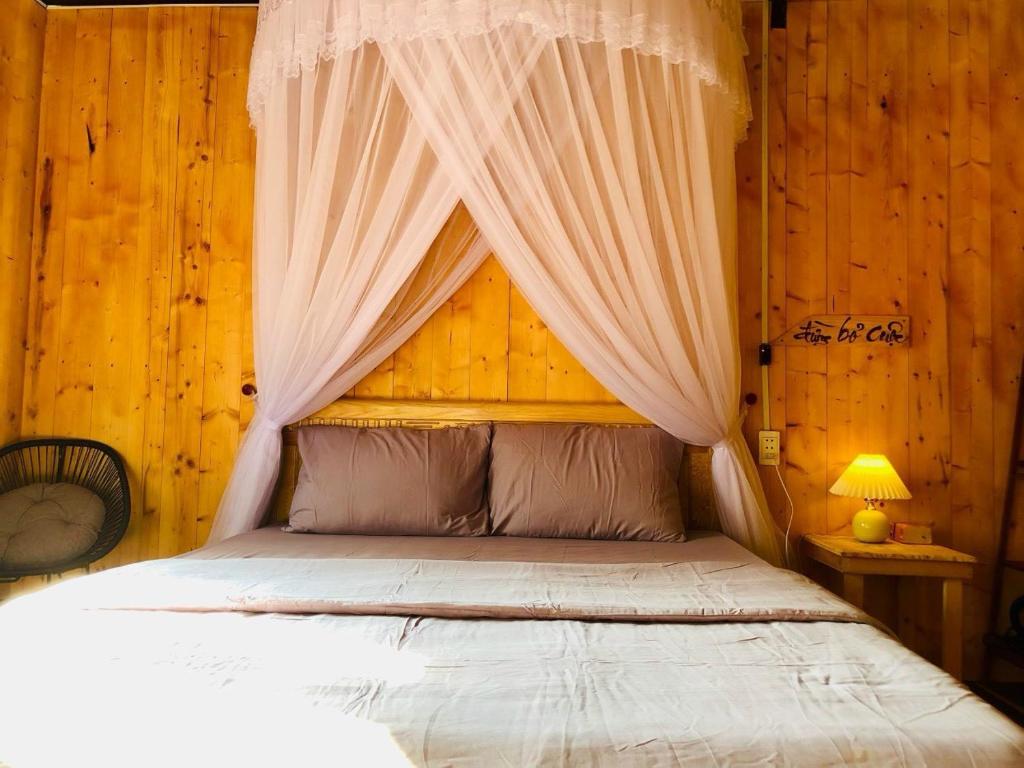 a bedroom with a bed with a mosquito net over it at Phú Cường Tà Đùng Farmstay in Biđong
