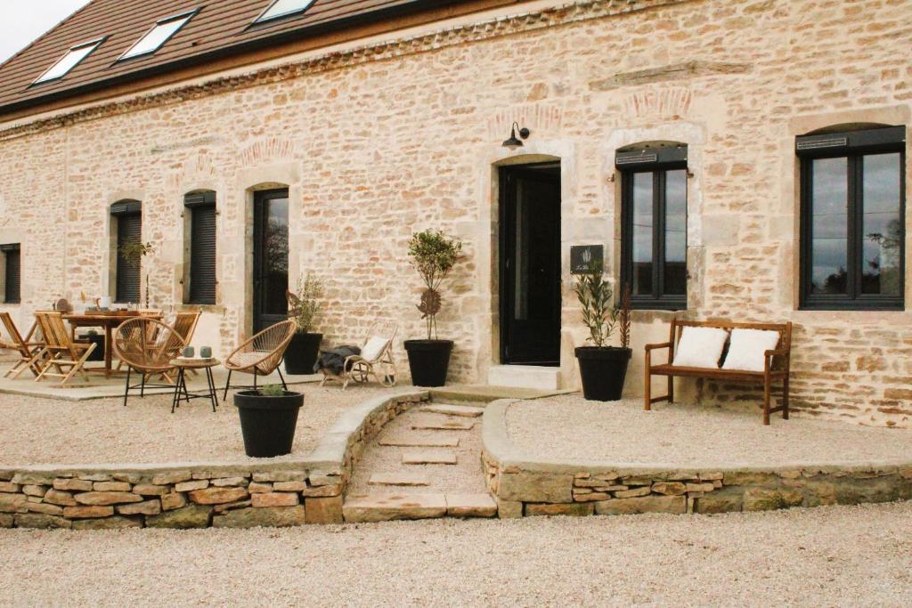 a brick building with a patio with a table and chairs at gîte les Blés Dorés in Corgengoux