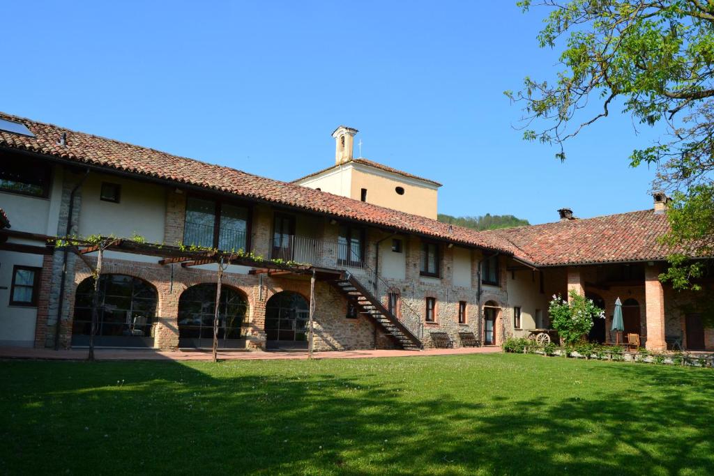 a large building with a grass yard in front of it at Agriturismo La Pieve in Dogliani