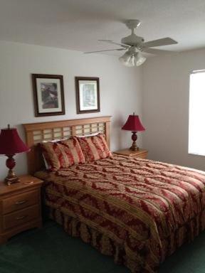 a bedroom with a bed with two lamps and a ceiling fan at Five-Bedroom Pool Home Davenport in Davenport