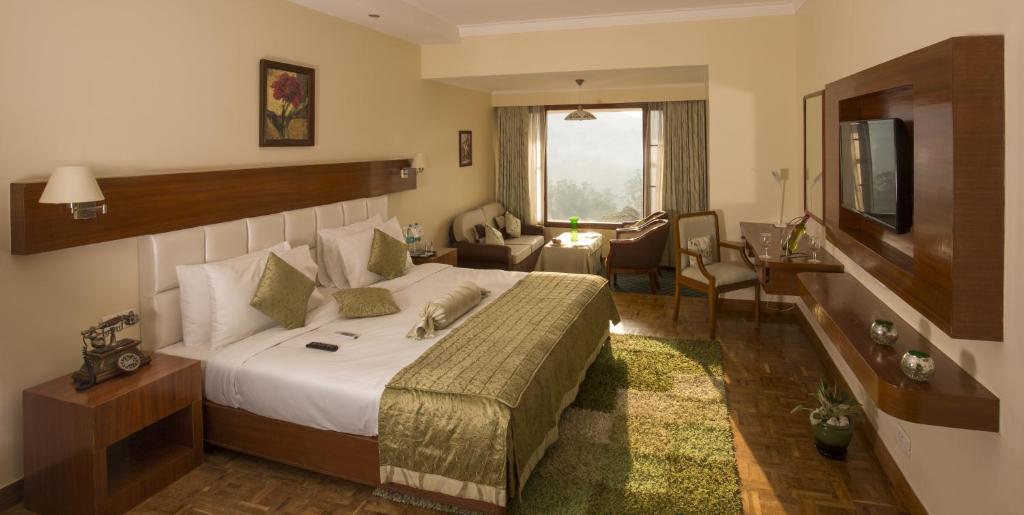 a hotel room with a bed and a living room at Gem Park Ooty in Ooty