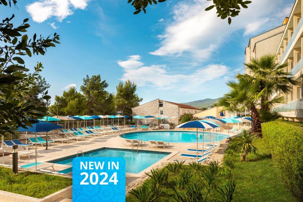 una piscina con una nueva señal de posada frente a un edificio en Rabac Sunny Hotel & Residence, en Rabac