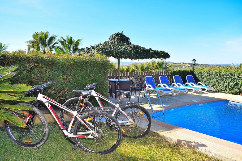 2 bicicletas están estacionadas junto a una piscina en Finca Can Xisco Domatiga 250 by Mallorca Charme, en Ariany