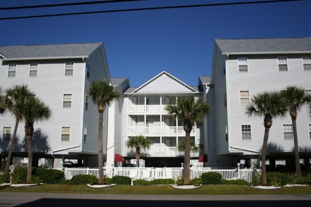 a large white building with palm trees in front of it at Ocean Pointe Unit A2 in Myrtle Beach