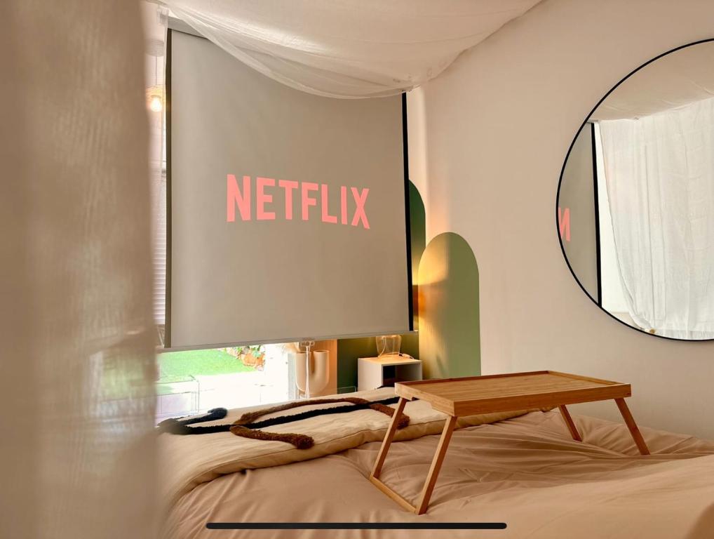 een bord op een muur boven een bed met een tafel bij Super Mini Loft avec Cinéma et Jardin - Cap d'Agde in Cap d'Agde