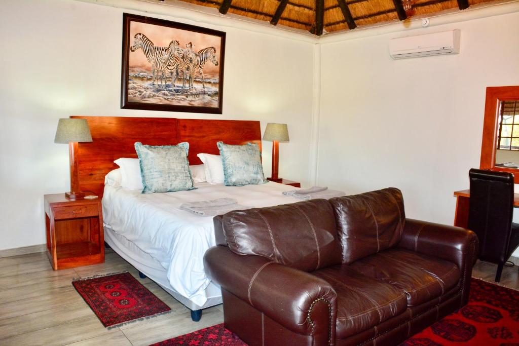 a bedroom with a bed and a leather couch at Lucca Lodge in Musina