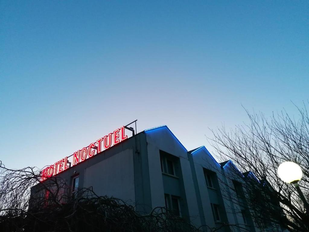 a building with a neon sign on top of it at HOTEL NOCTUEL in Rambouillet