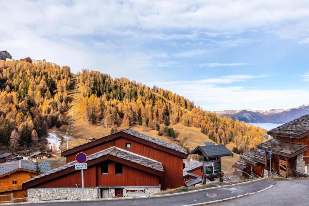 un bâtiment situé sur le côté d'une route à côté d'une montagne dans l'établissement Résidence Plagne Lauze - maeva Home - Studio 4 Personnes - Confort MAE-5774, à Mâcot La Plagne