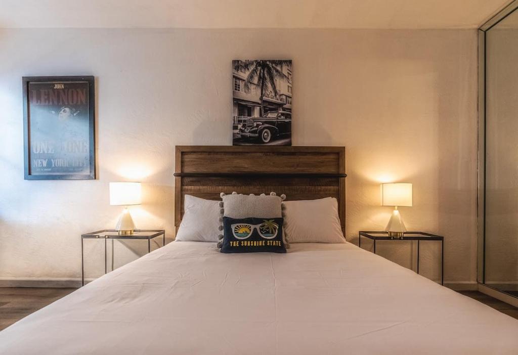 um quarto com uma grande cama branca e 2 candeeiros em Travelers Hideout Located 1 block from the beach em Miami Beach