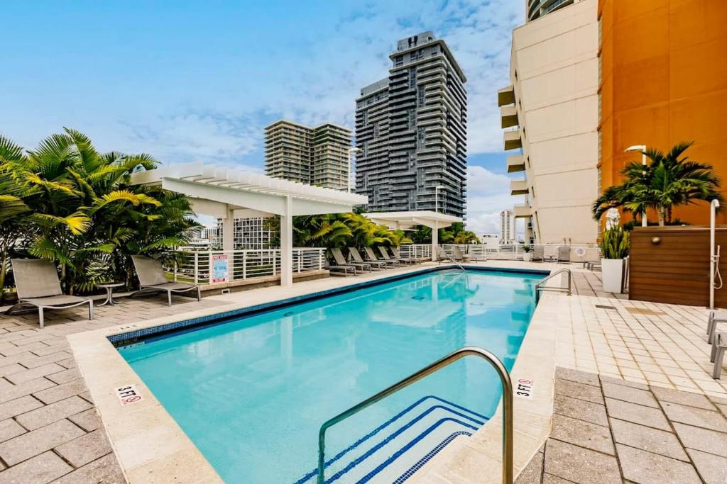 a swimming pool with chairs and a building at Palm Place Heart of Miami with Parking Pool and Gym in Miami
