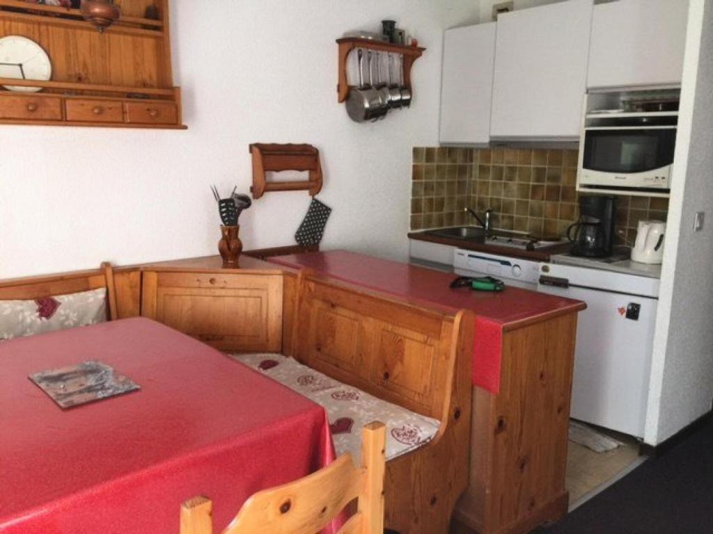 a kitchen with a table and a red counter top at Résidence Le Meale - Studio pour 6 Personnes 441 in Les Orres