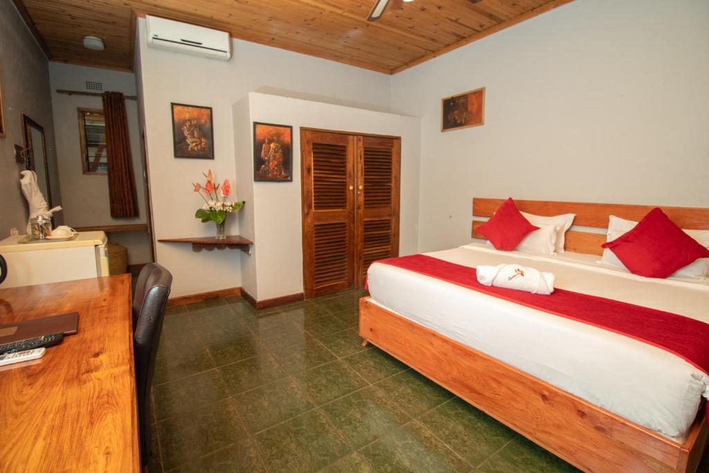 ein Schlafzimmer mit einem großen Bett und einem Schreibtisch in der Unterkunft SHERBOURNE LODGE in Kitwe