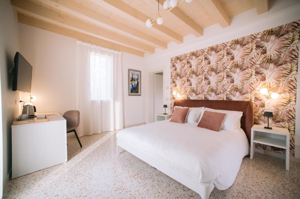 ein Schlafzimmer mit einem großen weißen Bett und einer Wand in der Unterkunft Locanda Golf Musella in San Martino Buon Albergo