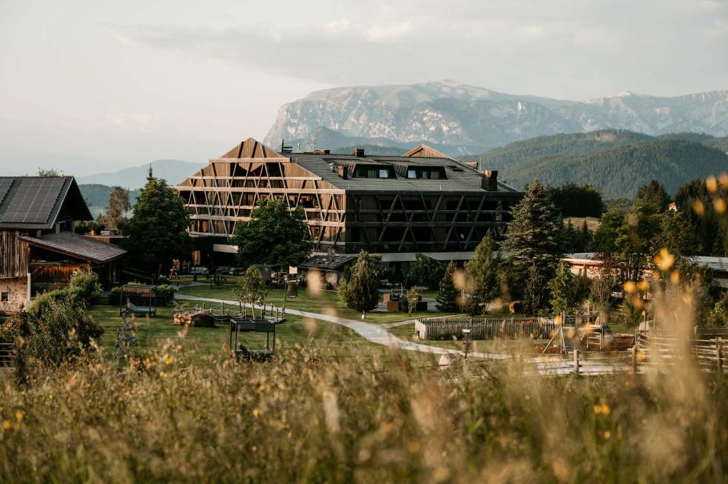 un resort con un grande edificio con montagne sullo sfondo di Naturhotel Pfösl a Nova Ponente