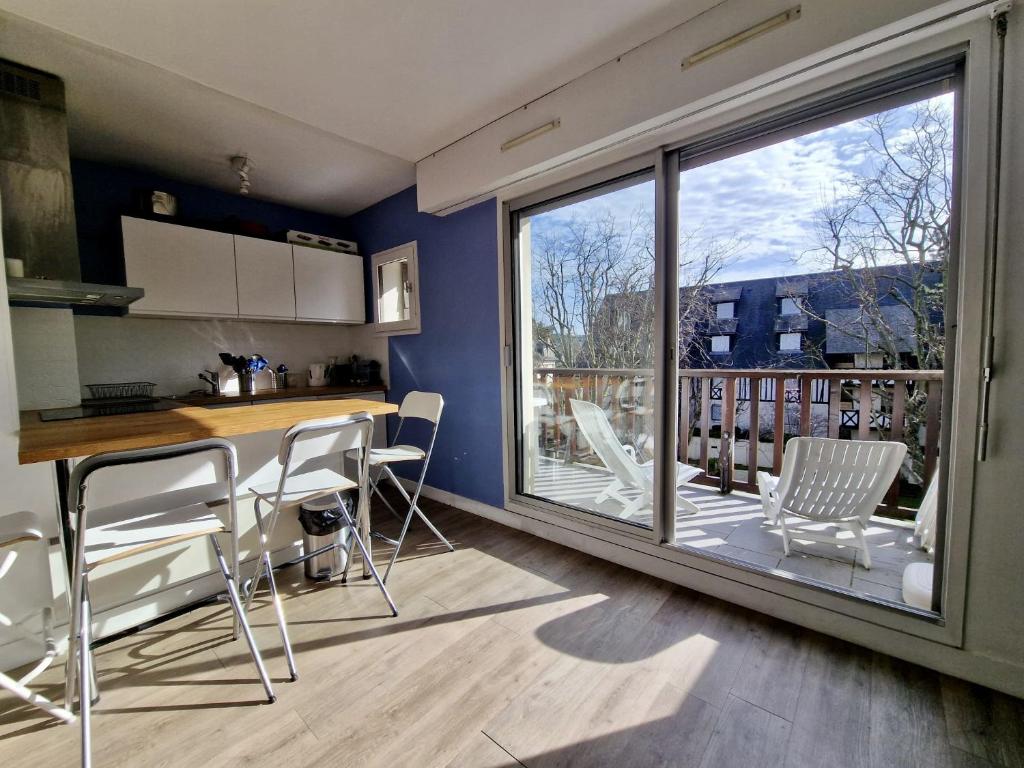 eine Küche mit einem Tisch und Stühlen sowie einen Balkon in der Unterkunft Appartement charmant bord de mer in Cabourg