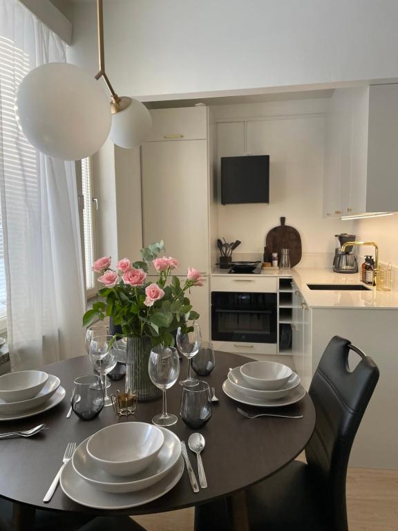 a kitchen with a table with plates and flowers on it at Seaside apt with parking space, close to metro (6mins from city centre) in Helsinki