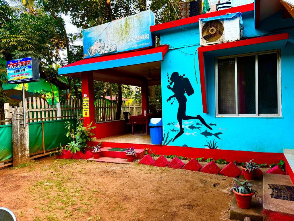 un edificio blu con un murale di una donna sopra di Royal Devbaug Holiday Home a Malwan
