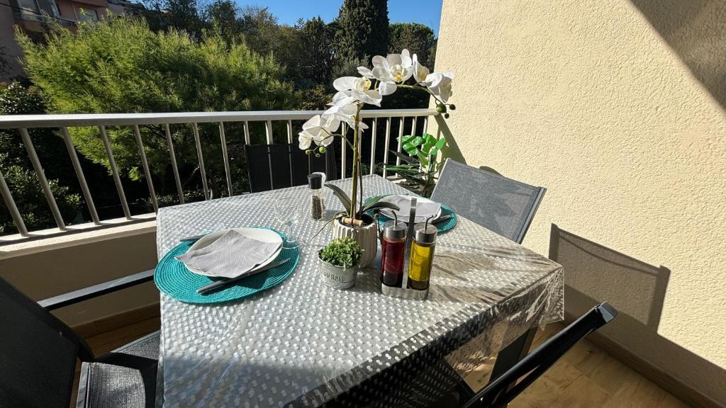 une table avec des assiettes, des serviettes et des fleurs sur un balcon dans l'établissement Proche Centre SANARY Studio climatisé 4 personnes, à Sanary-sur-Mer
