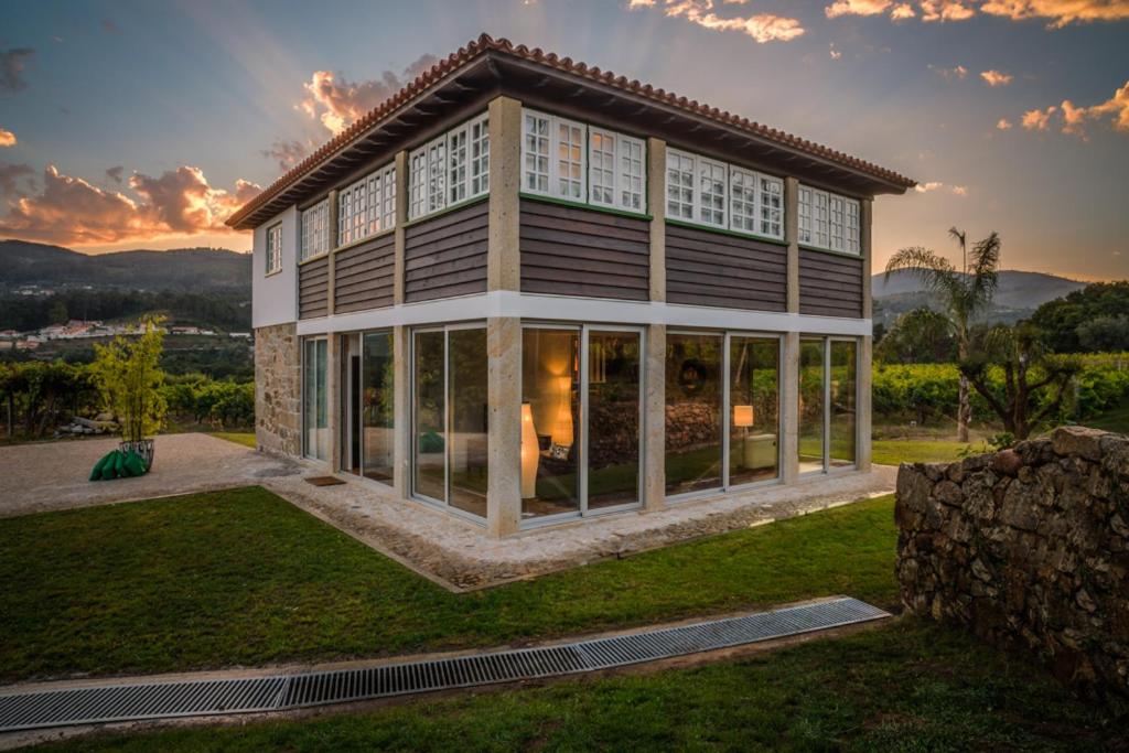 une maison avec de grandes fenêtres sur une pelouse dans l'établissement Casa da Vinha, à Arcos de Valdevez