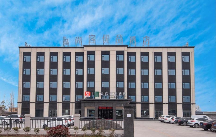 a large building with cars parked in a parking lot at Thank Inn Chain Jiaozuo Qinyang Qinbei Industral Cluster in Qinyang