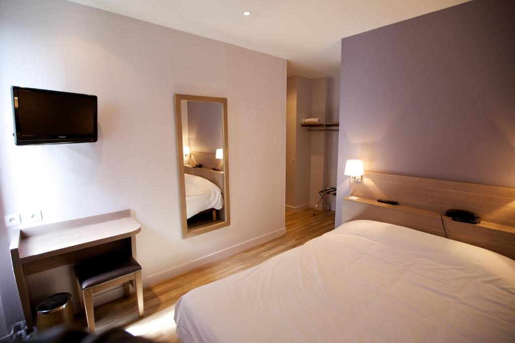 a hotel room with a bed and a sink and a mirror at Hôtel Montchapet Dijon Centre in Dijon