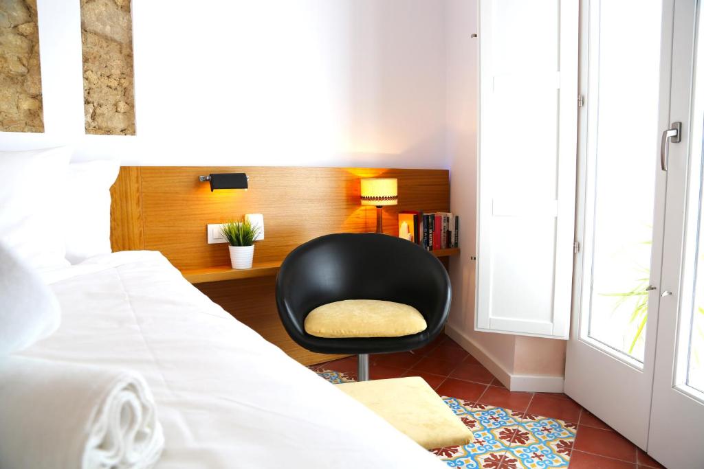 a bedroom with a black chair next to a bed at Vejerísimo Casa Boutique in Vejer de la Frontera